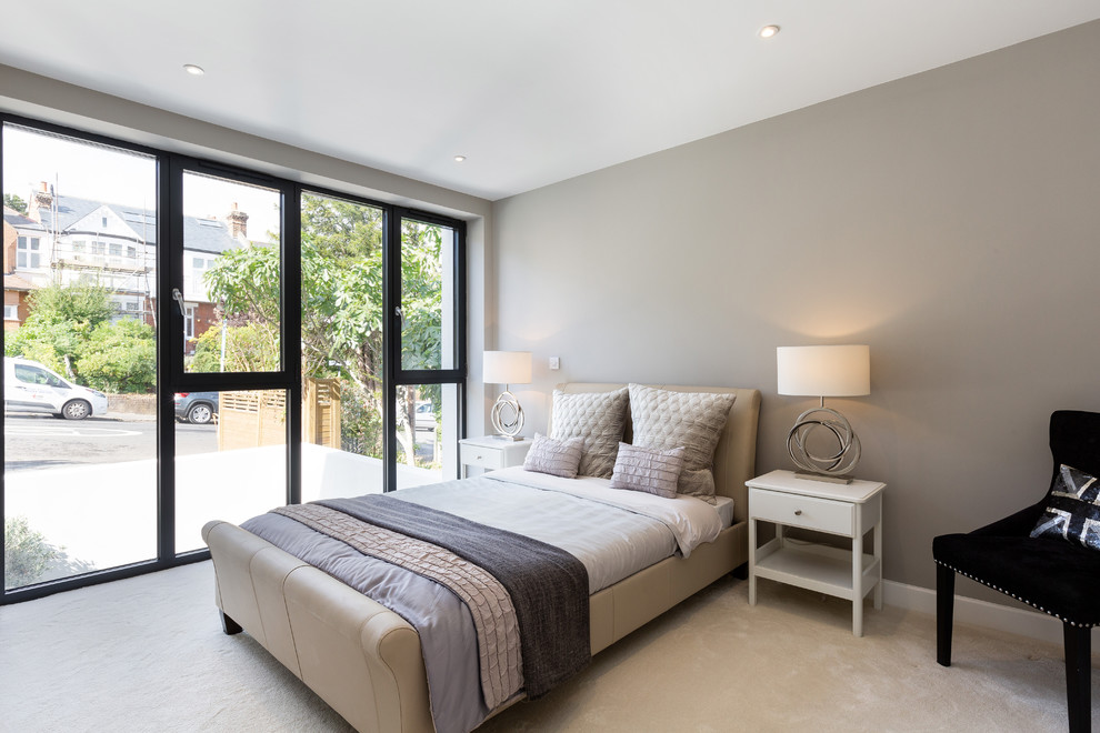 Mid-sized modern guest bedroom in London with beige walls, carpet, no fireplace and beige floor.
