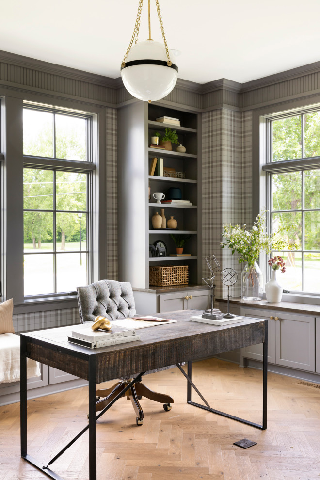 Inspiration for a transitional home office in Minneapolis with grey walls, medium hardwood floors, a freestanding desk, brown floor and wallpaper.