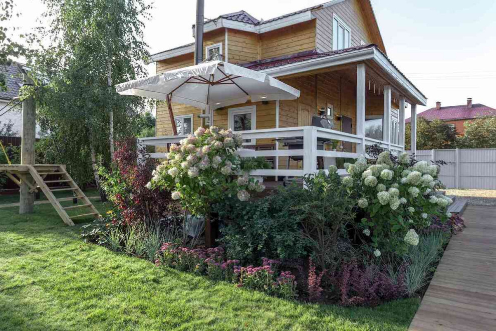 This is an example of a medium sized scandinavian side ground level wood railing terrace in Moscow with a bbq area and a roof extension.