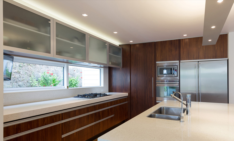 Inspiration for a large modern l-shaped eat-in kitchen in Auckland with an undermount sink, flat-panel cabinets, dark wood cabinets, granite benchtops, white splashback, stone slab splashback, stainless steel appliances, medium hardwood floors and with island.