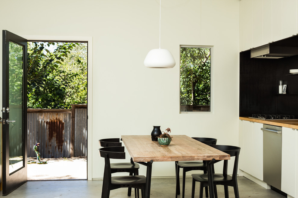 Photo of a mid-sized midcentury separate dining room in Austin with white walls, concrete floors and grey floor.