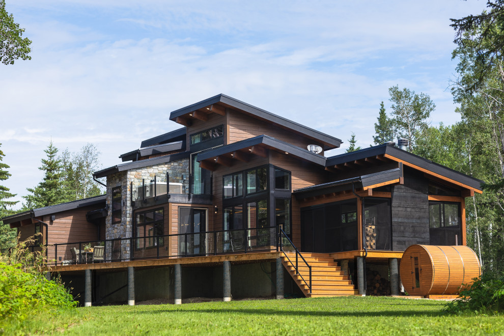 Idée de décoration pour une façade de maison marron chalet de taille moyenne et à un étage avec un revêtement mixte, un toit en appentis, un toit en métal et un toit noir.