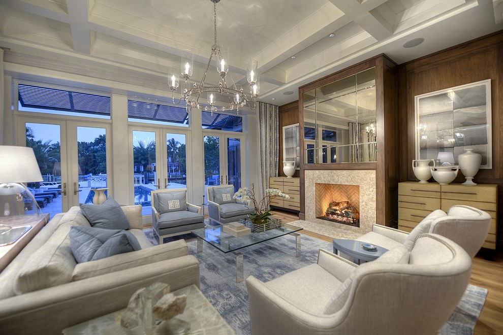 This is an example of a large transitional formal open concept living room in Miami with grey walls, medium hardwood floors, a standard fireplace, a stone fireplace surround and no tv.