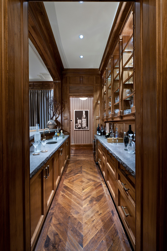 Photo of a large traditional galley wet bar in Miami with an undermount sink, recessed-panel cabinets, medium wood cabinets and medium hardwood floors.