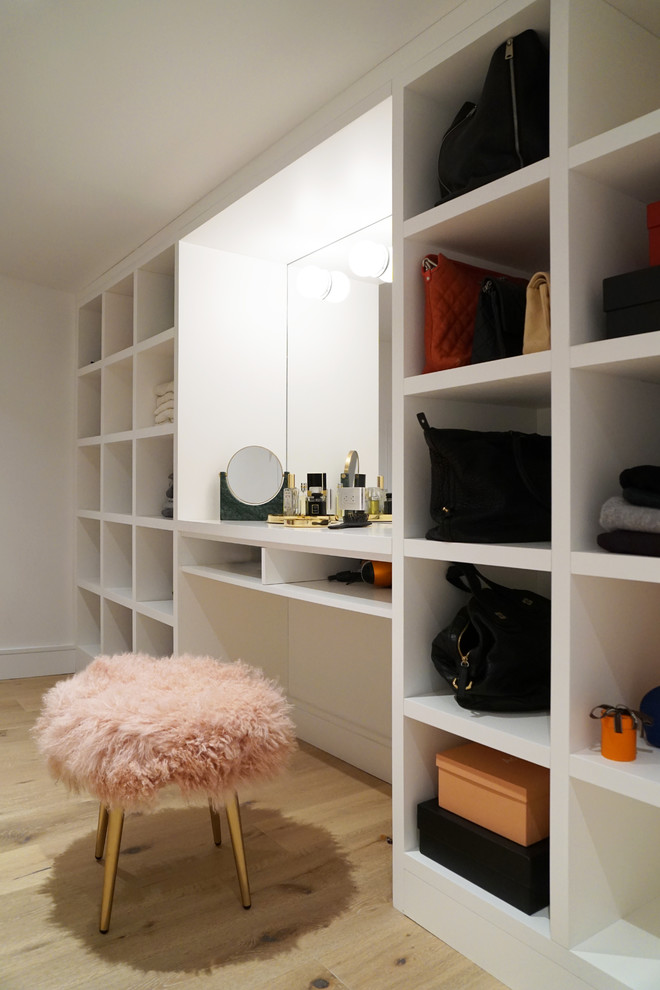 Inspiration for a mid-sized contemporary women's dressing room in New York with open cabinets, white cabinets, light hardwood floors and brown floor.