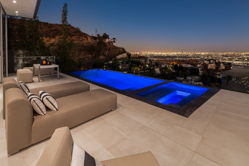 This is an example of a mid-sized contemporary backyard custom-shaped infinity pool in Los Angeles with a hot tub and tile.
