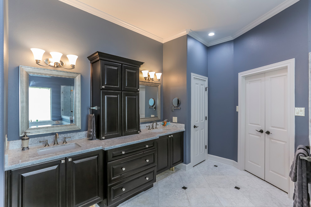 Design ideas for a large transitional master bathroom in Houston with raised-panel cabinets, a drop-in tub, an alcove shower, stone tile, blue walls, marble floors, an undermount sink, marble benchtops and black cabinets.