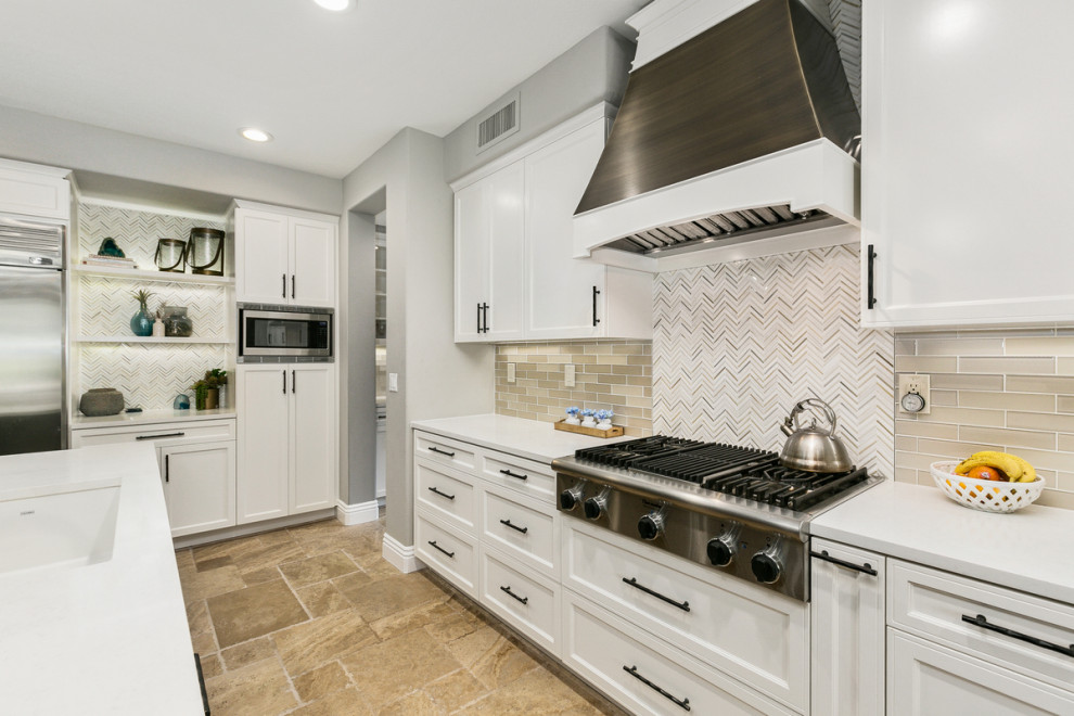Huge transitional u-shaped travertine floor and beige floor open concept kitchen photo in Orange County with a single-bowl sink, shaker cabinets, white cabinets, quartz countertops, multicolored backsplash, stone tile backsplash, stainless steel appliances, an island and white countertops