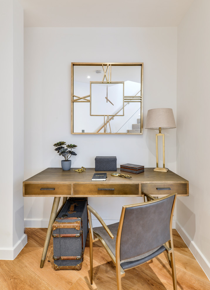 Inspiration for a mid-sized transitional home office in London with white walls, medium hardwood floors, a freestanding desk and brown floor.