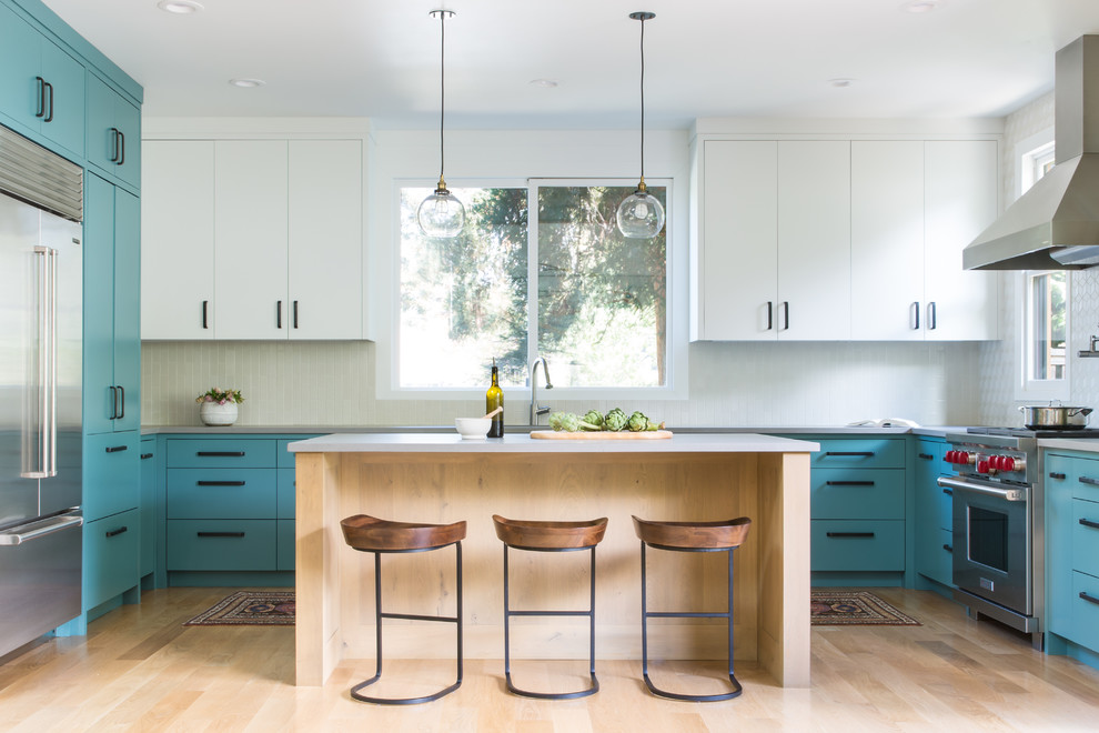 This is an example of a mid-sized midcentury u-shaped kitchen in San Francisco with flat-panel cabinets, turquoise cabinets, white splashback, with island, stainless steel appliances, light hardwood floors, beige floor and grey benchtop.