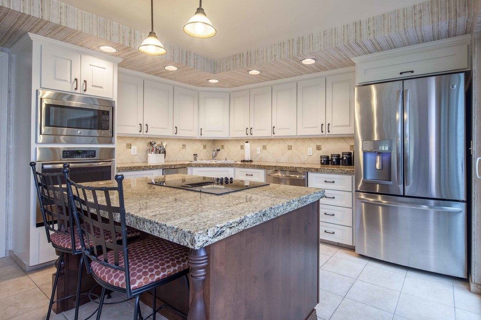 Example of a mid-sized transitional l-shaped ceramic tile and beige floor enclosed kitchen design with an undermount sink, raised-panel cabinets, white cabinets, ceramic backsplash, stainless steel appliances and an island