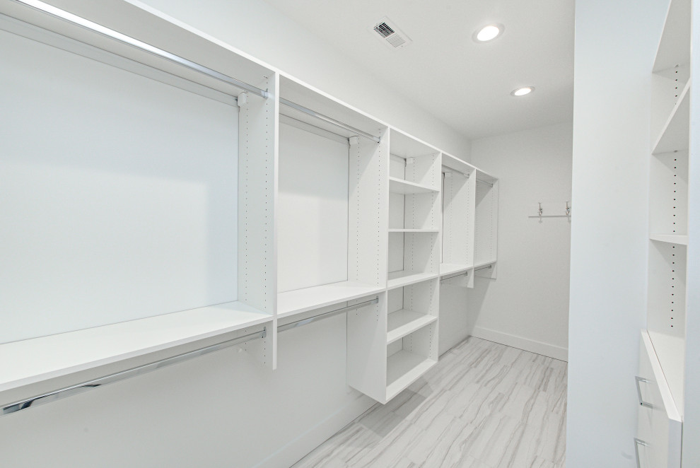 This is an example of a mid-sized gender-neutral walk-in wardrobe in Indianapolis with open cabinets, white cabinets, light hardwood floors and white floor.