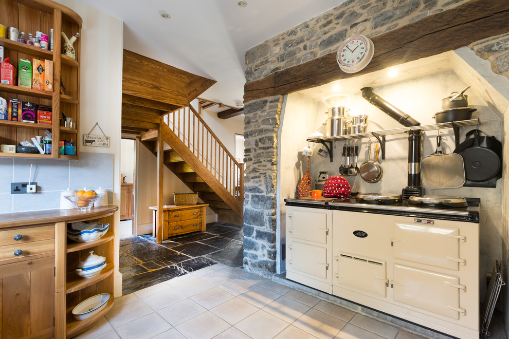 This is an example of a country u-shaped kitchen in Devon with flat-panel cabinets, medium wood cabinets, grey splashback and white appliances.
