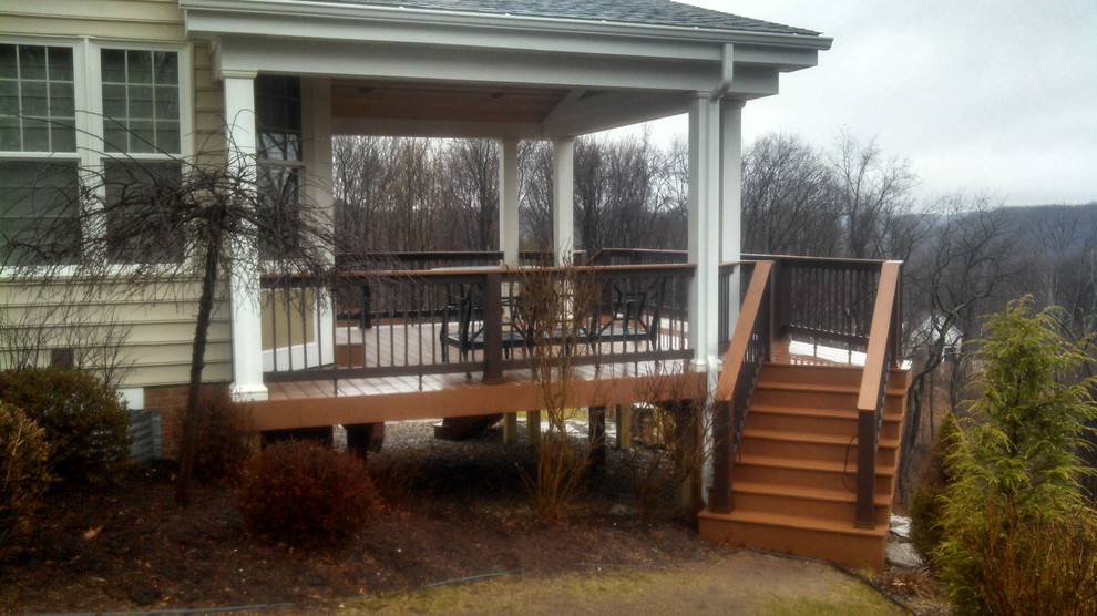 Mid-sized elegant backyard deck photo with a roof extension