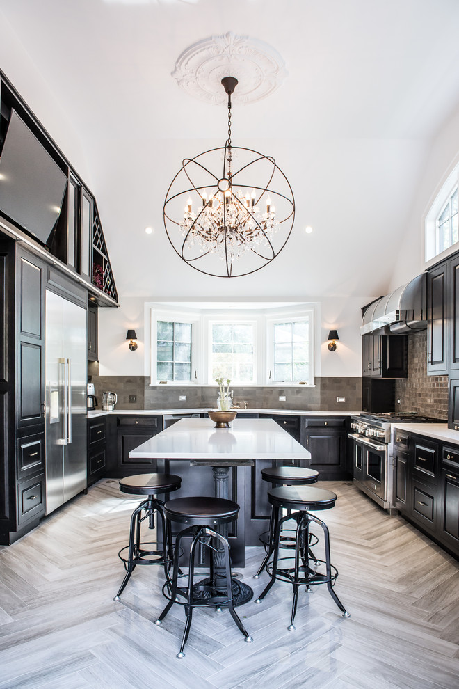 This is an example of a large transitional u-shaped eat-in kitchen in New York with black cabinets, stainless steel appliances, with island, raised-panel cabinets, an undermount sink, solid surface benchtops, grey splashback, ceramic splashback and porcelain floors.
