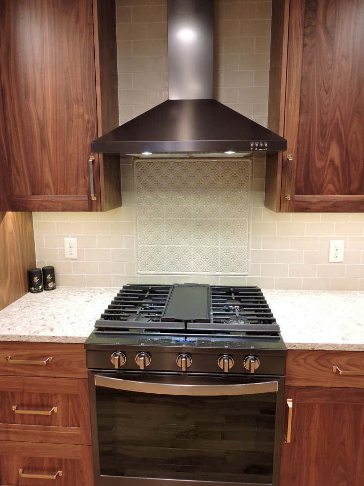 Arts and crafts galley light wood floor eat-in kitchen photo with recessed-panel cabinets, dark wood cabinets, quartzite countertops, beige backsplash, ceramic backsplash, black appliances and beige countertops