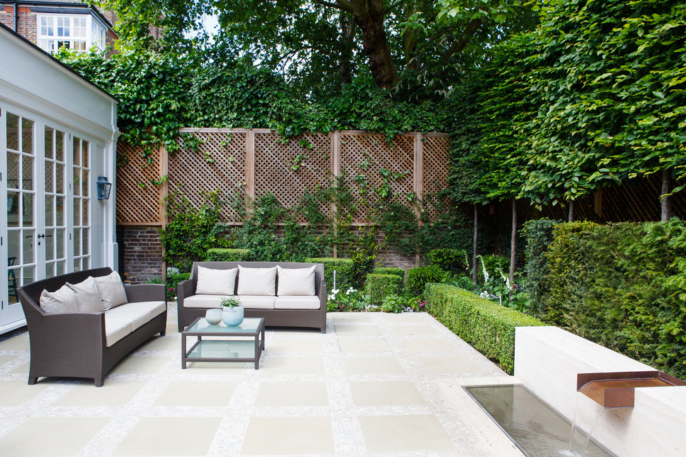 This is an example of a small traditional courtyard patio in London with natural stone pavers.