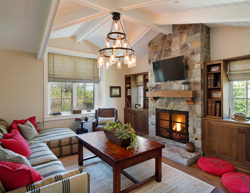 Photo of a country living room in San Diego with beige walls, a standard fireplace and a stone fireplace surround.