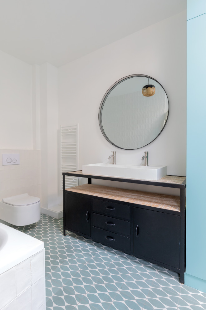 Bild på ett stort shabby chic-inspirerat beige beige en-suite badrum, med släta luckor, svarta skåp, ett platsbyggt badkar, en dusch/badkar-kombination, en vägghängd toalettstol, vit kakel, perrakottakakel, vita väggar, cementgolv, ett avlångt handfat, träbänkskiva, blått golv och med dusch som är öppen