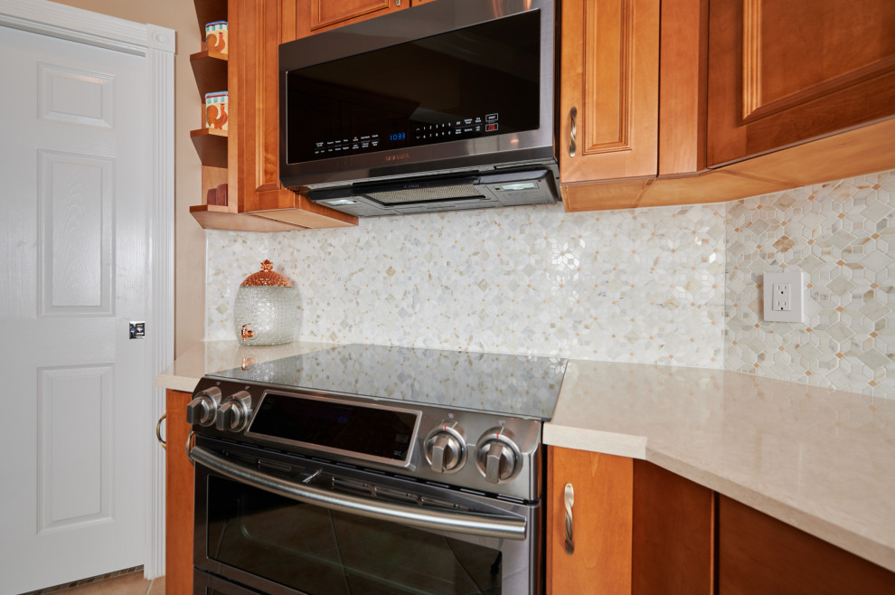 Inspiration for a mid-sized transitional galley porcelain tile, beige floor and tray ceiling kitchen remodel in Miami with a farmhouse sink, recessed-panel cabinets, medium tone wood cabinets, quartz countertops, multicolored backsplash, marble backsplash, stainless steel appliances, a peninsula and beige countertops