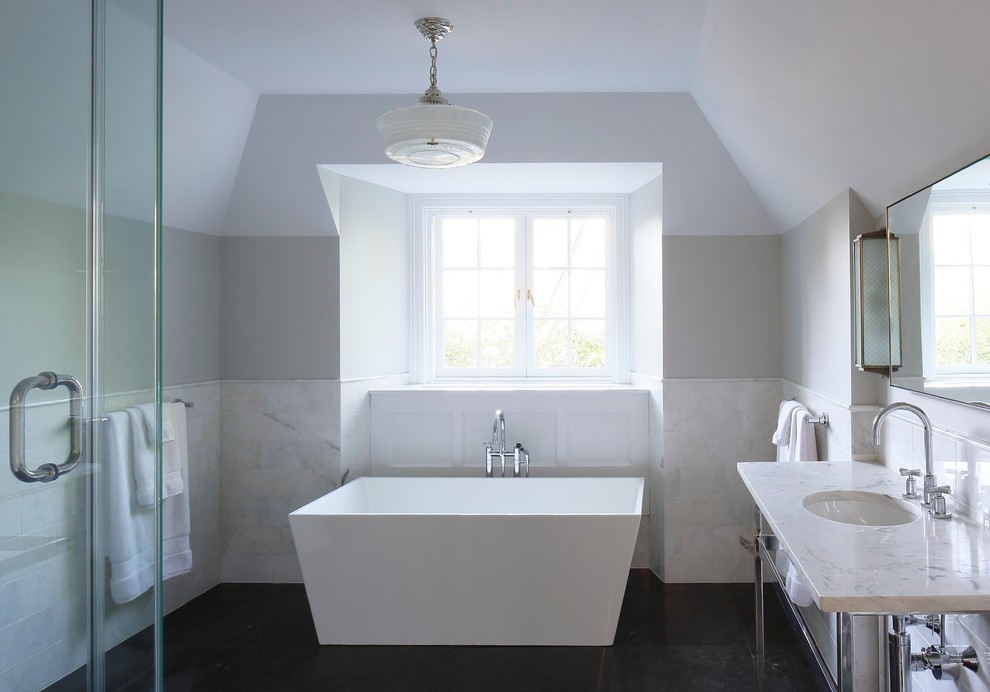 This is an example of a large transitional kids bathroom in New York with an undermount sink, open cabinets, marble benchtops, a freestanding tub, a corner shower, a one-piece toilet, white tile, stone tile, white walls and marble floors.