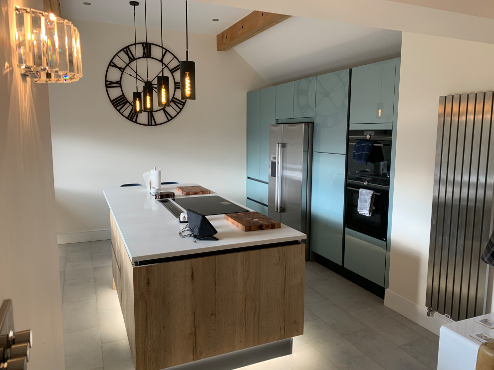 Photo of a large industrial kitchen in Buckinghamshire with flat-panel cabinets, blue cabinets, quartzite benchtops, stainless steel appliances, with island, grey floor and white benchtop.