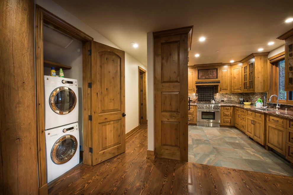 Open concept kitchen - mid-sized rustic u-shaped slate floor and gray floor open concept kitchen idea with an undermount sink, raised-panel cabinets, medium tone wood cabinets, quartzite countertops, black backsplash, ceramic backsplash, stainless steel appliances, no island and brown countertops