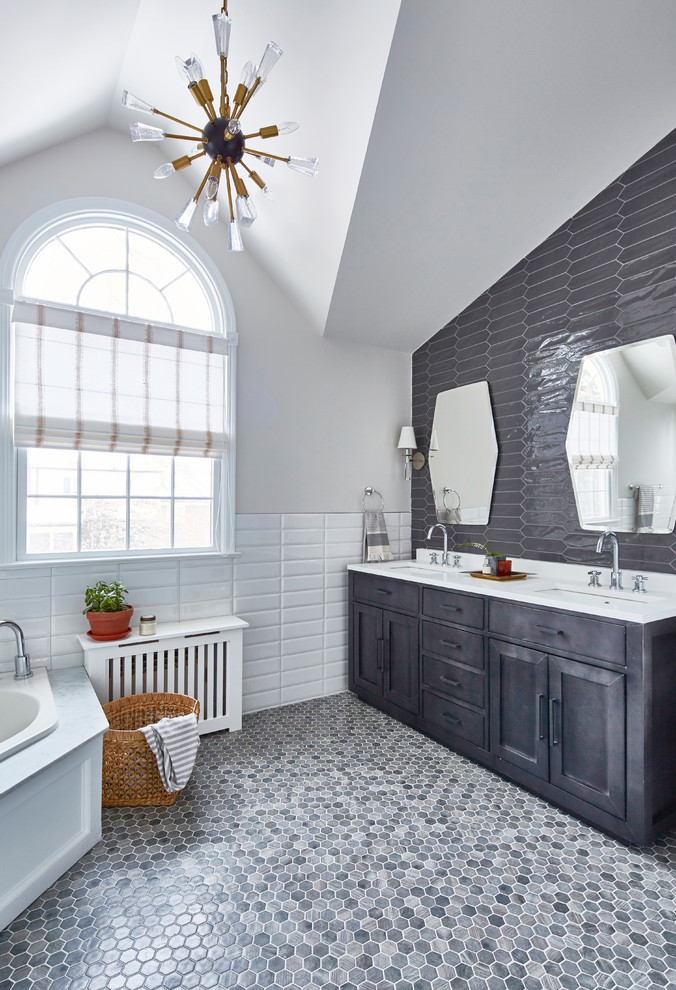 This is an example of a mid-sized transitional master bathroom in New York with grey cabinets, a corner tub, white tile, gray tile, ceramic tile, grey walls, engineered quartz benchtops, shaker cabinets, an undermount sink, grey floor and white benchtops.