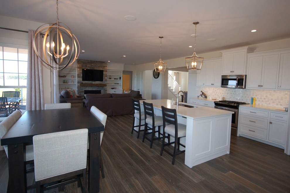 Inspiration for a mid-sized transitional l-shaped dark wood floor and brown floor open concept kitchen remodel with a single-bowl sink, shaker cabinets, white cabinets, solid surface countertops, white backsplash, ceramic backsplash and an island
