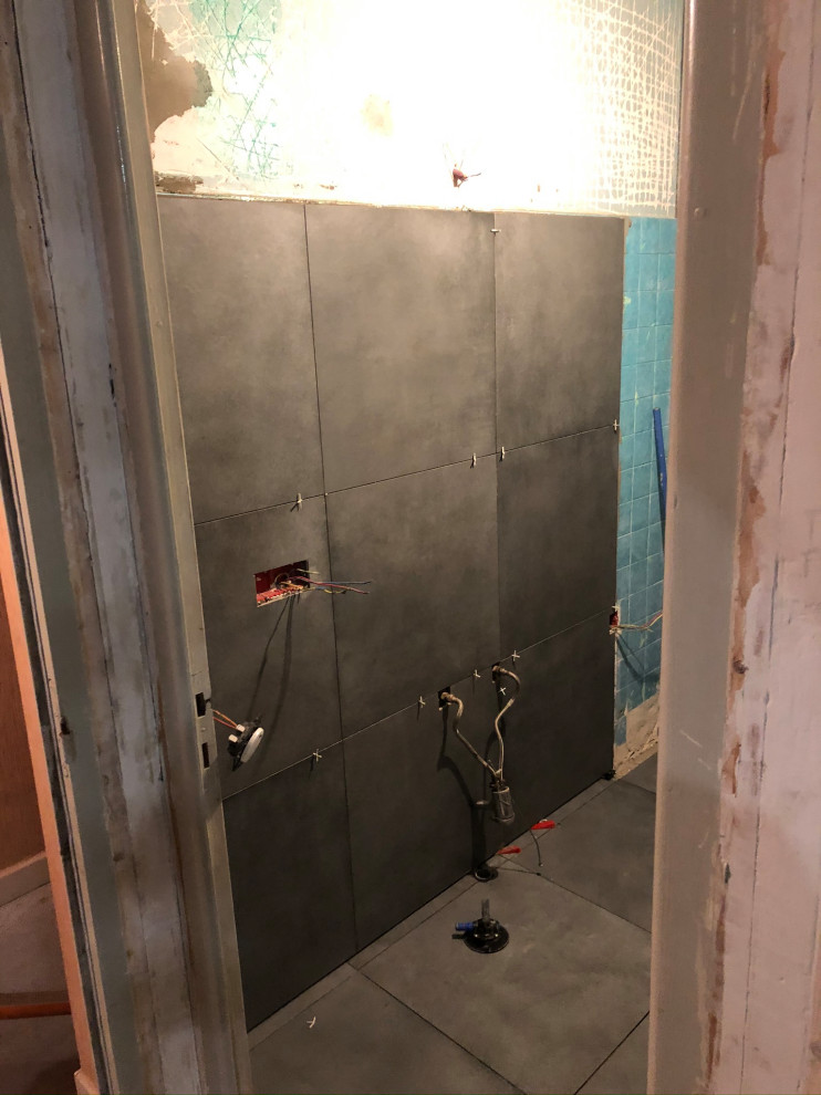 Bild på ett litet funkis badrum med dusch, med skåp i mellenmörkt trä, en dusch i en alkov, en vägghängd toalettstol, grå kakel, stenkakel, grå väggar, ett nedsänkt handfat, grått golv och dusch med gångjärnsdörr