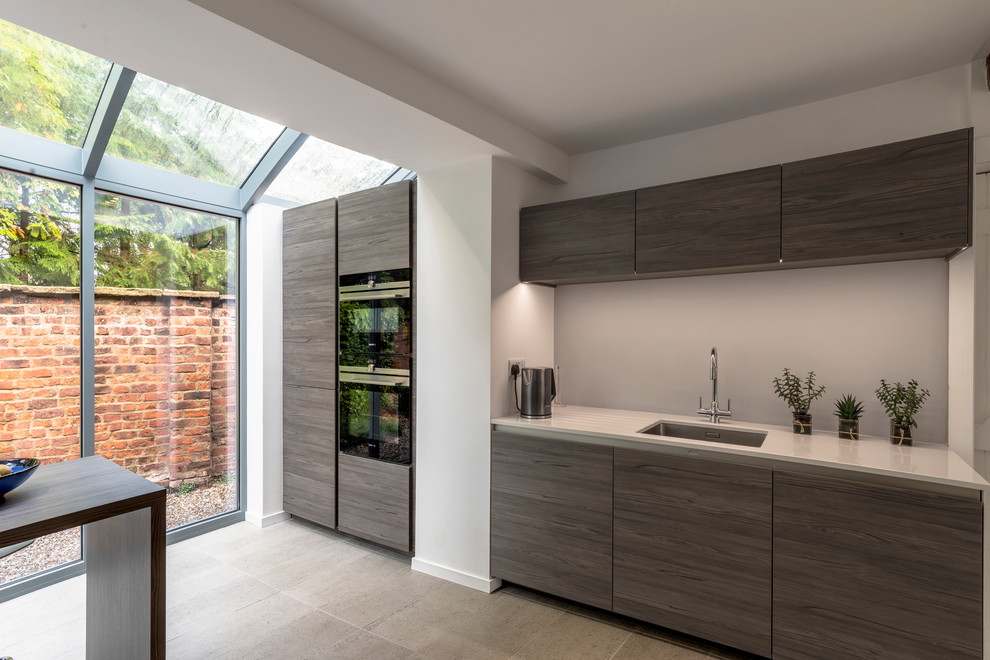 Contemporary kitchen in Cheshire with flat-panel cabinets, black appliances, ceramic floors and beige floor.