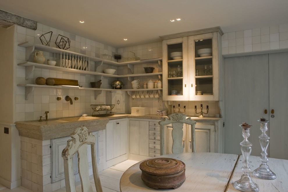 Inspiration for a mid-sized traditional l-shaped eat-in kitchen in New York with a double-bowl sink, distressed cabinets, white splashback, glass-front cabinets, limestone benchtops, porcelain splashback, white appliances, limestone floors and with island.
