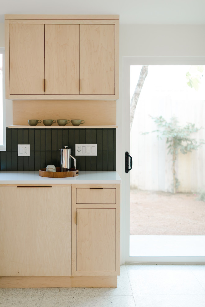 Photo of a mid-sized scandinavian l-shaped open plan kitchen in Los Angeles with beige cabinets, green splashback, ceramic splashback, white appliances, concrete floors, with island, white floor and white benchtop.