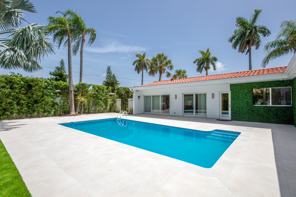 Inspiration pour un piscine avec aménagement paysager minimaliste de taille moyenne et rectangle avec une cour et du carrelage.