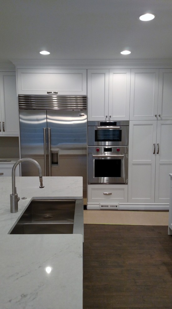 Eat-in kitchen - large transitional l-shaped eat-in kitchen idea with a farmhouse sink, flat-panel cabinets, white cabinets, quartz countertops, stainless steel appliances and two islands