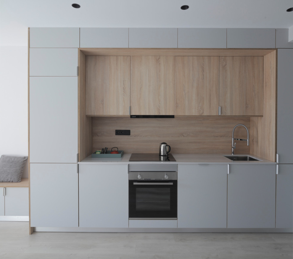 Inspiration for a small modern single-wall open plan kitchen in Barcelona with a drop-in sink, recessed-panel cabinets, grey cabinets, quartz benchtops, beige splashback, timber splashback, panelled appliances, light hardwood floors, no island, beige floor, grey benchtop and recessed.
