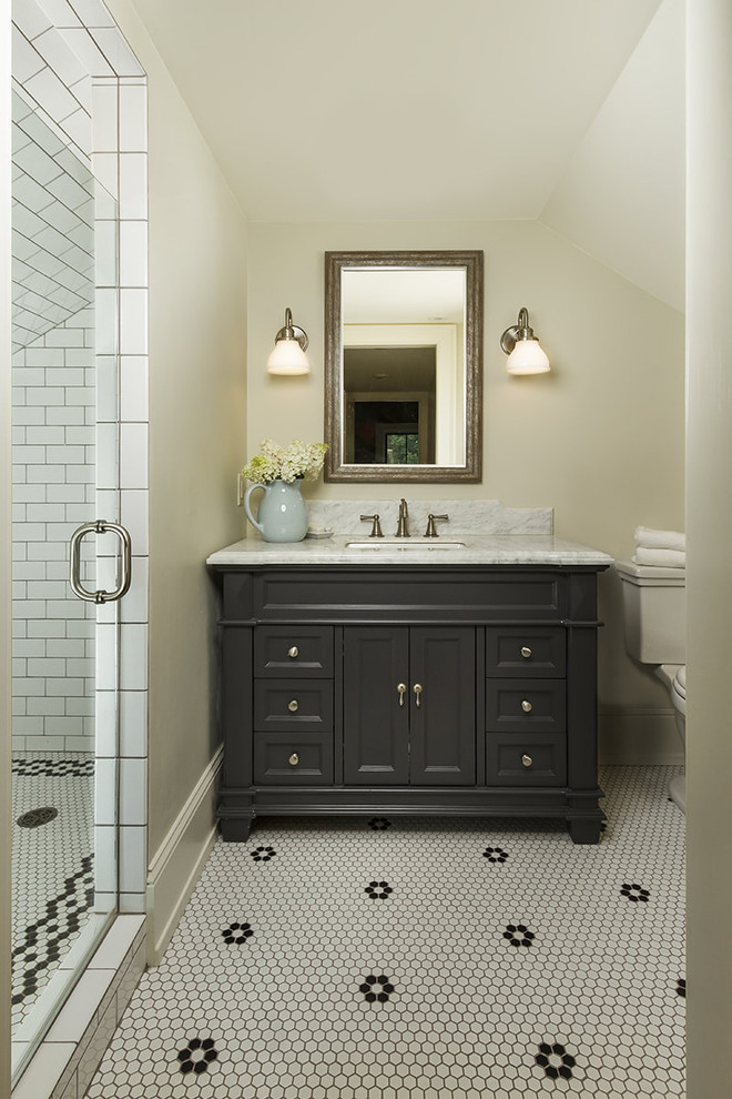 Photo of a country bathroom in DC Metro with black cabinets, a two-piece toilet, white tile, subway tile, beige walls, mosaic tile floors, an undermount sink, multi-coloured floor and recessed-panel cabinets.