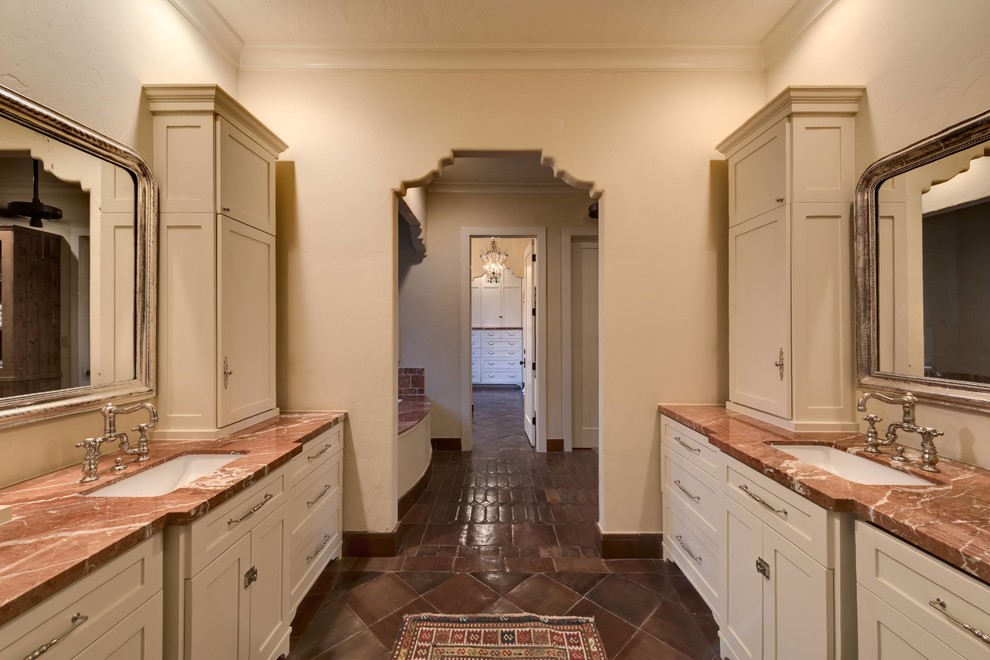 Design ideas for a mid-sized mediterranean master bathroom in Houston with shaker cabinets, beige cabinets, an undermount tub, an alcove shower, a two-piece toilet, stone tile, beige walls, terra-cotta floors, an undermount sink, marble benchtops and brown tile.