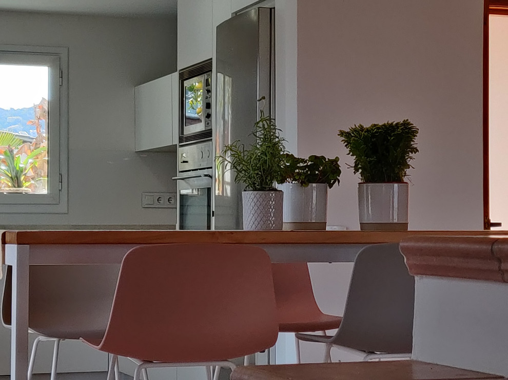 Design ideas for a medium sized u-shaped open plan kitchen in Barcelona with a submerged sink, flat-panel cabinets, white cabinets, white splashback, stainless steel appliances, terracotta flooring, an island, pink floors and a timber clad ceiling.