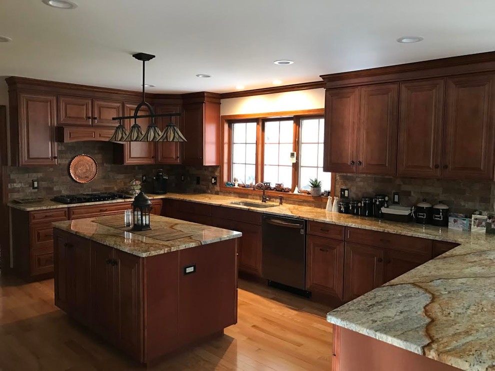 Inspiration for a transitional l-shaped light wood floor open concept kitchen remodel in Orange County with a single-bowl sink, raised-panel cabinets, medium tone wood cabinets, quartzite countertops, brown backsplash, black appliances and an island