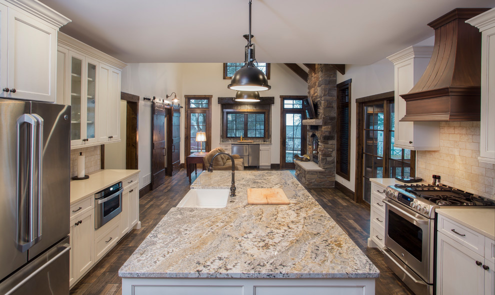 Example of a mid-sized medium tone wood floor open concept kitchen design with white cabinets, granite countertops, stainless steel appliances and an island