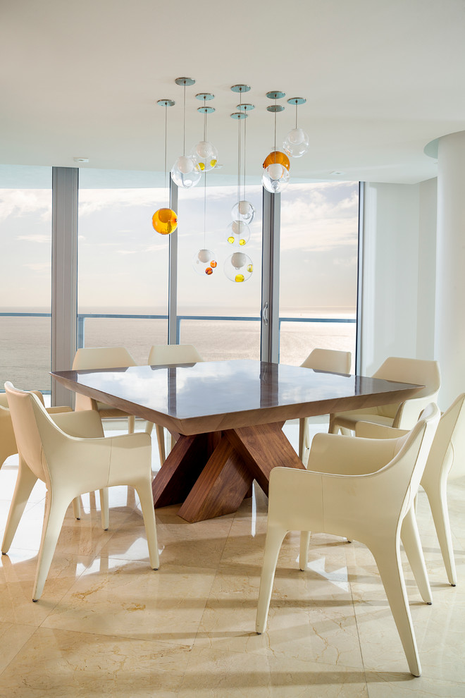 This is an example of a large beach style dining room in Miami with white walls and marble floors.