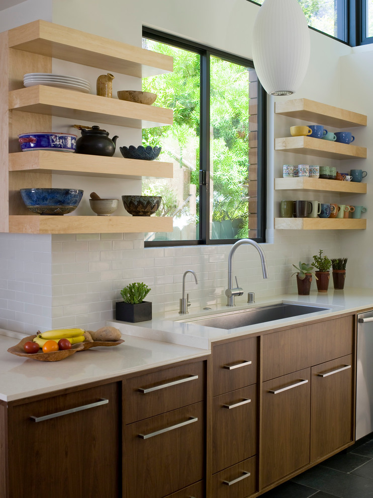 Inspiration for a mid-sized contemporary open plan kitchen in Los Angeles with an undermount sink, flat-panel cabinets, dark wood cabinets, white splashback, subway tile splashback, stainless steel appliances, quartzite benchtops, slate floors, no island and grey floor.