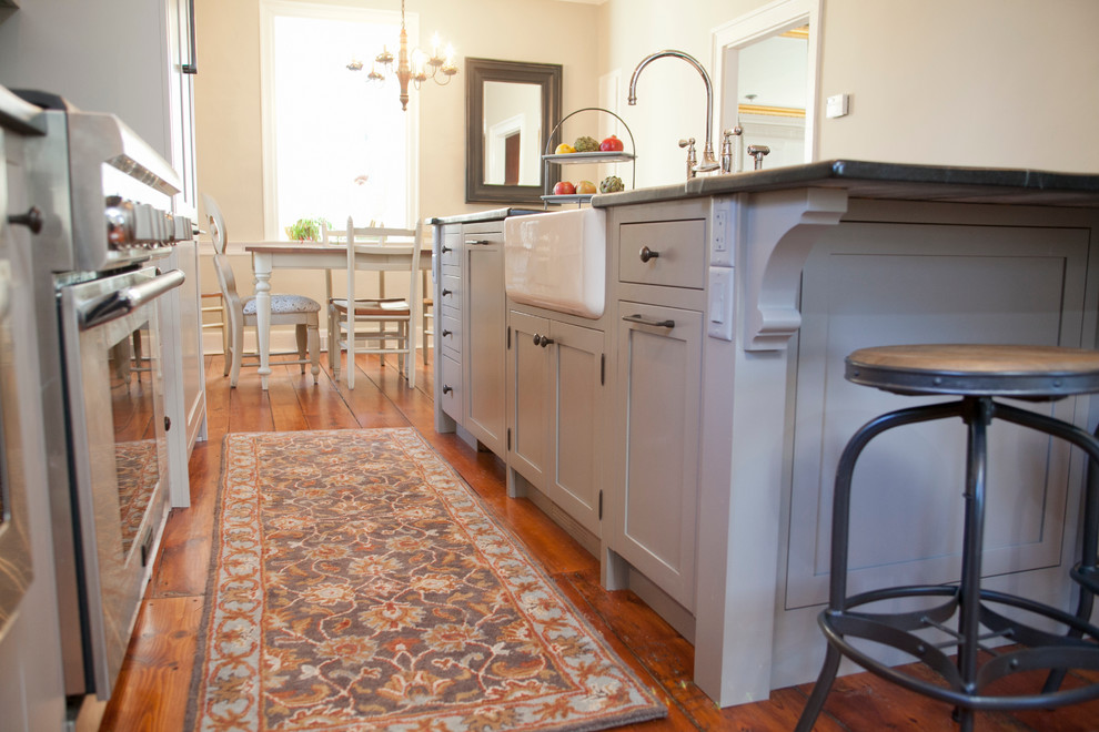 Large country galley eat-in kitchen in Philadelphia with a farmhouse sink, shaker cabinets, grey cabinets, soapstone benchtops, stainless steel appliances, medium hardwood floors and with island.