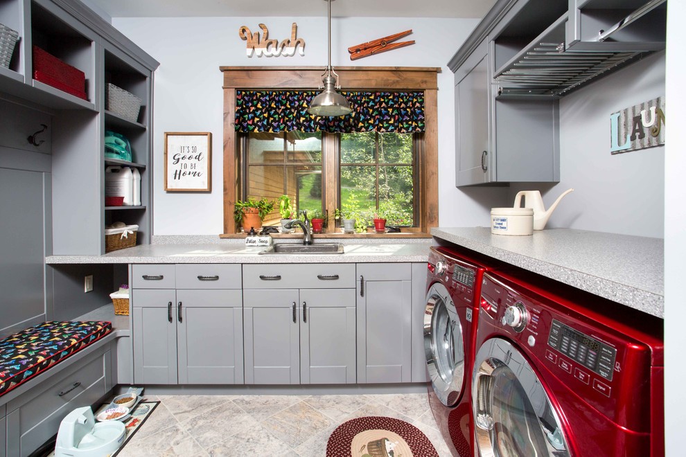 This is an example of a mid-sized u-shaped utility room in Other with a drop-in sink, shaker cabinets, grey cabinets, laminate benchtops, grey walls, ceramic floors, a side-by-side washer and dryer and grey floor.