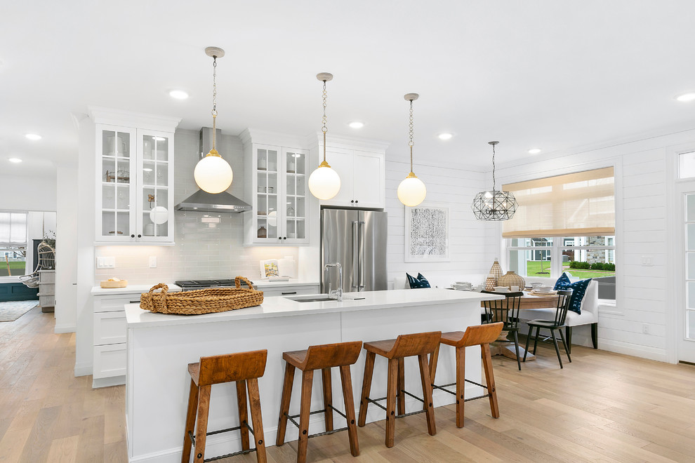 Photo of a transitional galley eat-in kitchen in New York with an undermount sink, shaker cabinets, white cabinets, quartz benchtops, stainless steel appliances, with island, white benchtop, light hardwood floors and blue floor.
