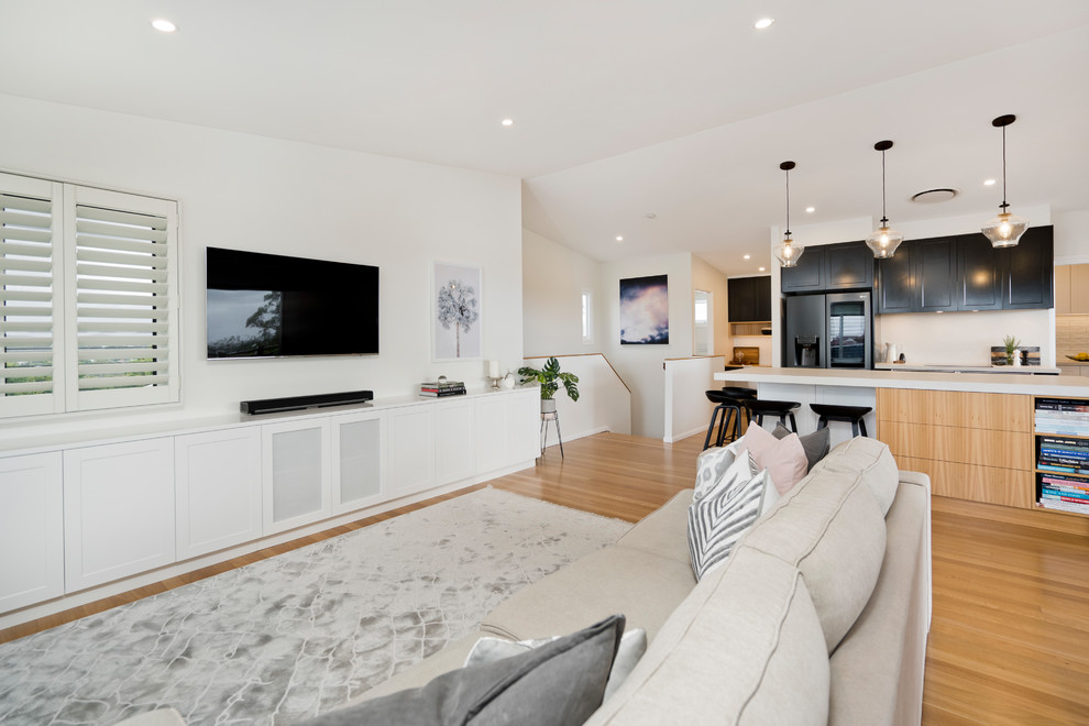 Large contemporary open concept living room in Brisbane with white walls, light hardwood floors, a wall-mounted tv and beige floor.
