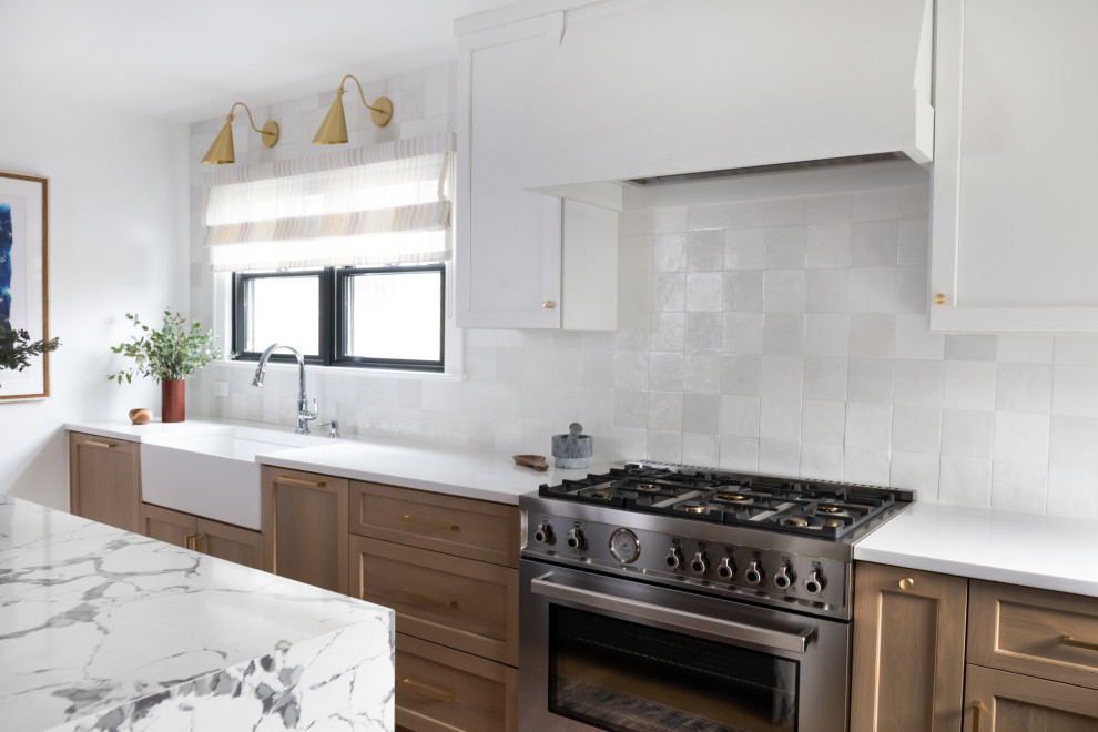 Inspiration for a small transitional l-shaped separate kitchen in New York with a farmhouse sink, shaker cabinets, light wood cabinets, quartz benchtops, white splashback, ceramic splashback, stainless steel appliances, medium hardwood floors, with island and white benchtop.