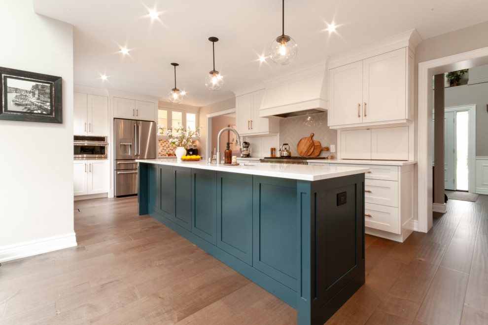 Example of a large transitional galley medium tone wood floor and brown floor eat-in kitchen design in Toronto with an undermount sink, recessed-panel cabinets, white cabinets, quartz countertops, gray backsplash, porcelain backsplash, stainless steel appliances, an island and white countertops