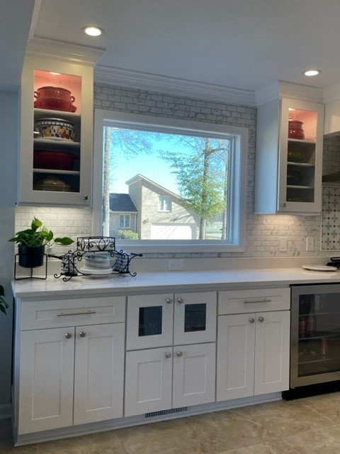 Large transitional l-shaped open concept kitchen photo with shaker cabinets, white cabinets, quartzite countertops, white backsplash, ceramic backsplash, stainless steel appliances, an island and white countertops